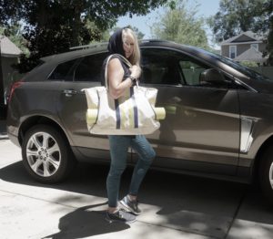 Woman getting into a car while carrying yoga mat.