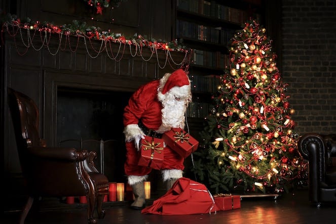 Christmas night, Santa Claus puts gifts under the tree