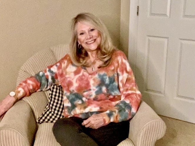 Woman sitting in a chair while wearing a tie dye sweater