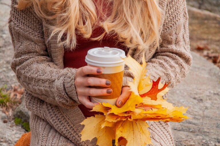 Woman-holding-cup-of-coffee-in-the-hands-outdoor-in-autumn-park