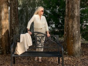 Woman wearing white standing behind a park bench