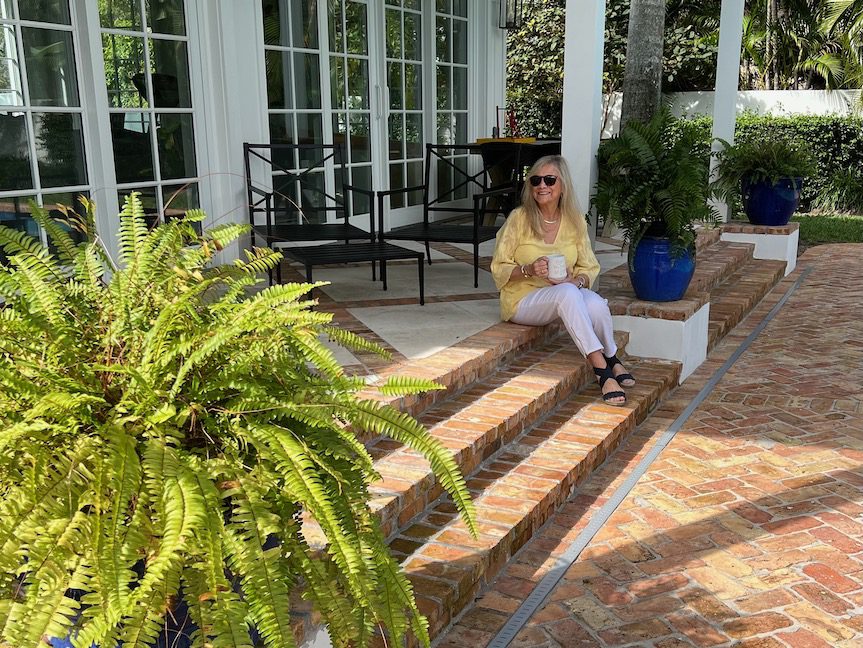 Woman sitting on porch steps with a cup of coffee.