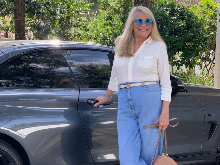 Woman standing beside a car wearing the current trend of denim for women over 50