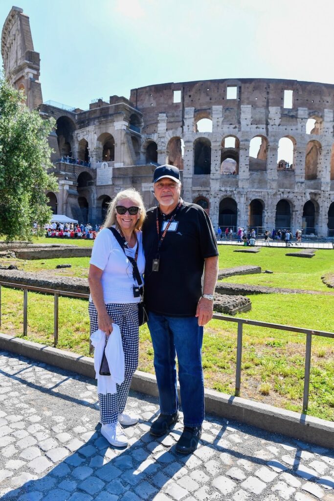 A woman and a man stood before the Coliseum in Rome, Italy.