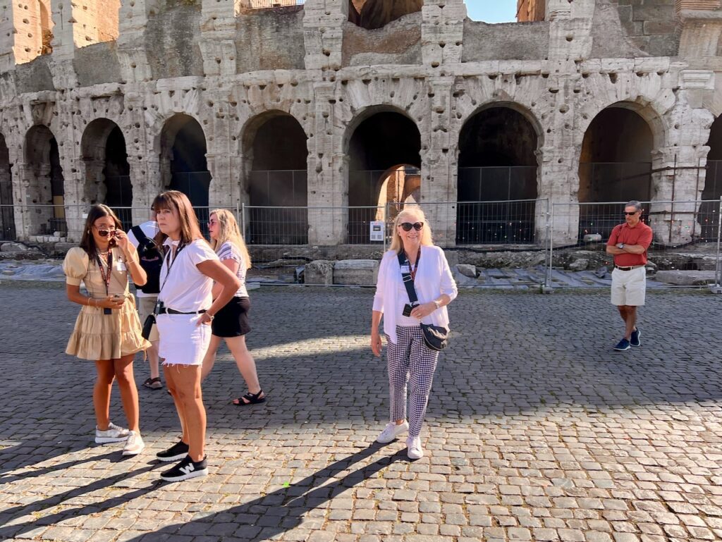 Women standing outside the entrance to the Coliseum in Rome, Italy.