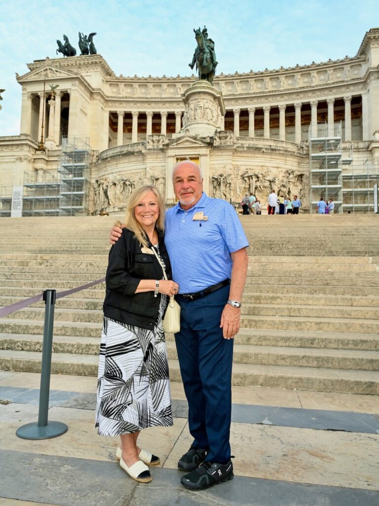 A man and woman standing on the stairs of the Vittoriano - Wedding Cake in Rome, Italy.
