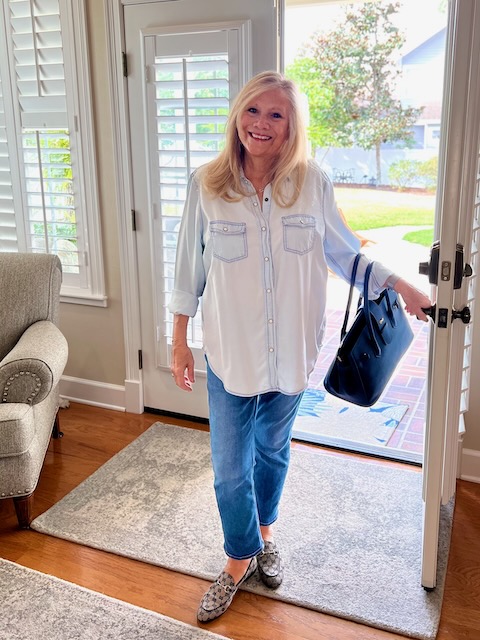 A blonde woman is standing in an open doorway. She is dressed in a chambray shirt and denim jeans. How to Rock Your Jeans in January post.