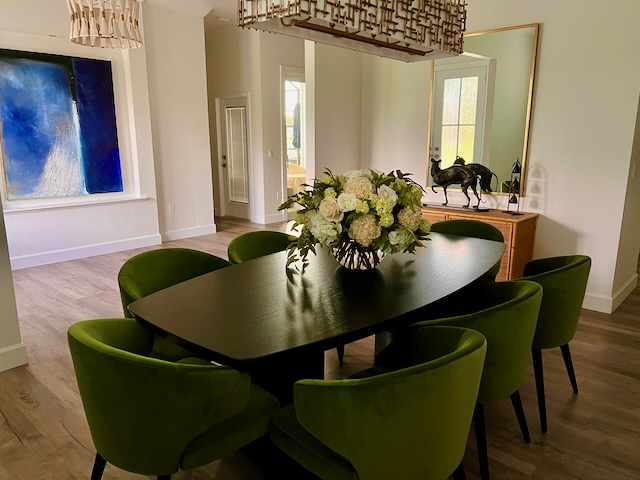 A modern dining room showcasing a gold mirror hanging over a rattan chest.