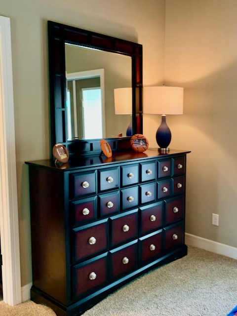 A dark wood dresser with mirror on top.
