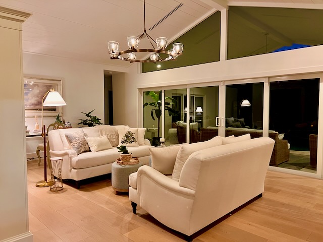 Coastal style living room with white facing loveseats and brass chandelier