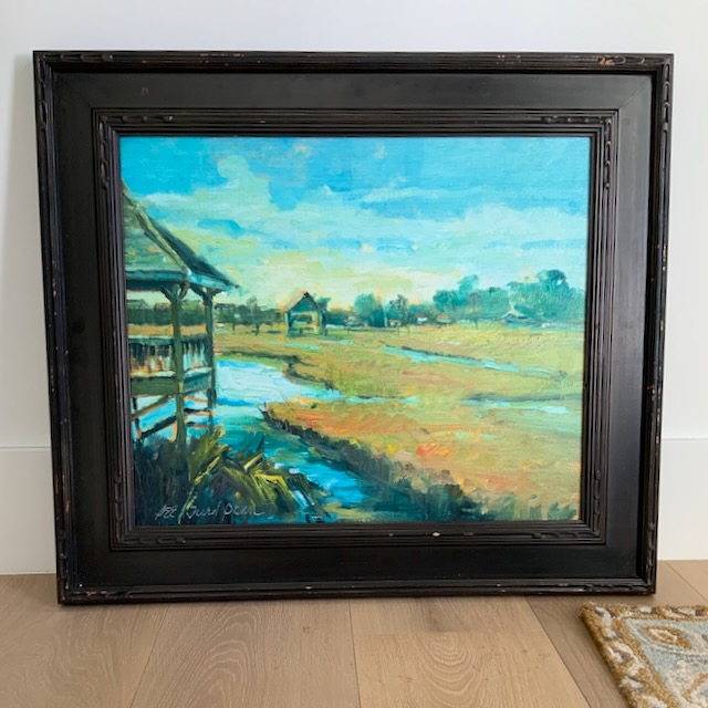 Coastal oil painting framed in a heavy, dark frame.